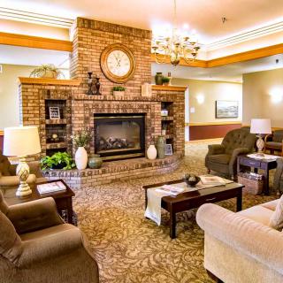 A cozy living room featuring a brick fireplace, surrounded by comfortable sofas and armchairs, with warm lighting and elegant decor.