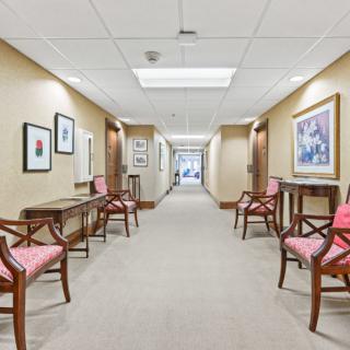 A well-lit corridor with chairs and artwork lining the walls.