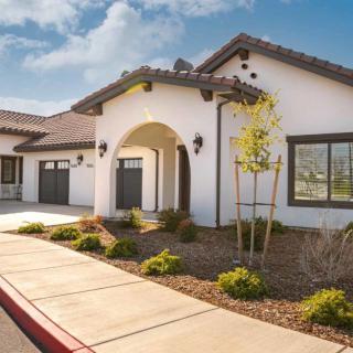 A modern residential house with a landscaped front yard and driveway, captured on a sunny day.