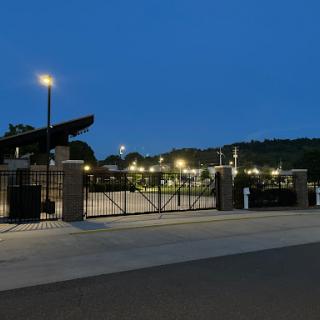 A view of a well-lit sports facility gate during dusk.