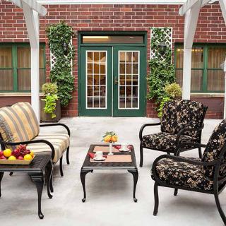 A cozy outdoor patio with stylish seating and potted plants against a brick wall.