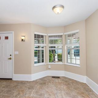 A bright living room with a bay window and tiled flooring.