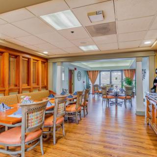 A cozy dining area with wooden flooring and neatly arranged tables and chairs.