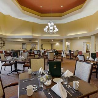 A spacious dining area with neatly arranged tables and a central chandelier.