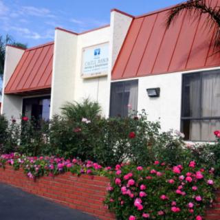 A building with a red roof and vibrant garden in the foreground on a sunny day.
