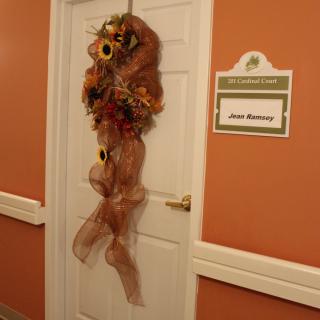 A decorated door with an autumn-themed wreath featuring sunflowers inside a building.