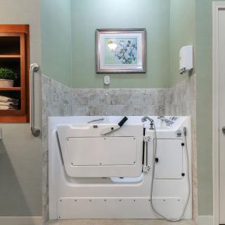 A bathroom featuring an accessible walk-in bathtub with tiled walls.