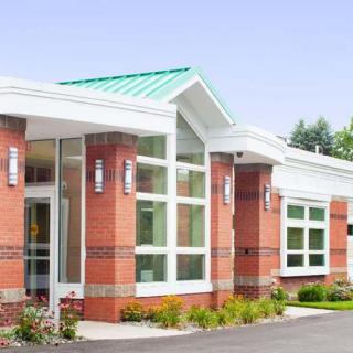 A modern brick building exterior with large windows and a green roof.
