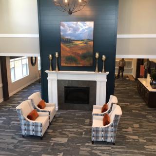 A welcoming lobby interior featuring a fireplace, comfortable seating, and decorative artwork.
