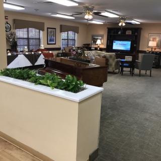 A cozy lobby area with comfortable seating, a television, and decorative plants.