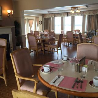 A well-lit dining room with elegantly set tables and chairs.