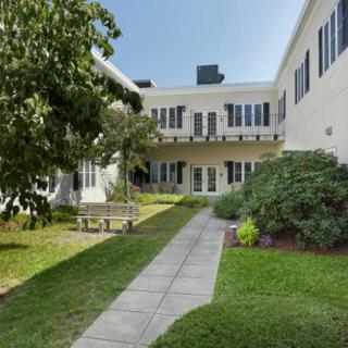 A serene courtyard with a garden path leading to a building surrounded by lush greenery.
