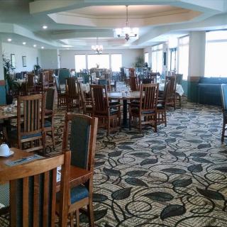 An empty restaurant dining room with neatly arranged tables and chairs on a patterned carpet.