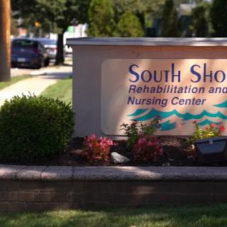 Entrance sign for South Shore Rehabilitation and Nursing Center surrounded by flowers and shrubs.