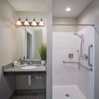 A modern bathroom featuring a sleek vanity with a mirror and a separate shower area.