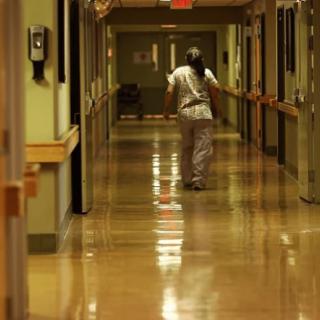 A nurse walks down a hospital corridor.