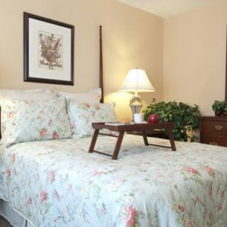 A cozy bedroom with a floral comforter and a tray on the bed.