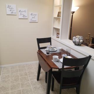 A small dining area with a table set for two, featuring art on the wall and a warm interior ambiance.