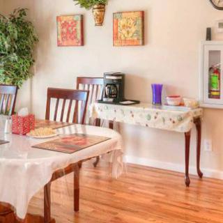 A cozy dining room with a table and chairs, adorned with artwork and a coffee station.