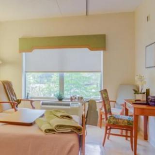 A cozy bedroom with a large window, comfortable chairs, and neatly arranged furniture.