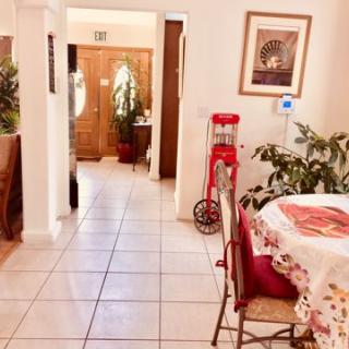 A cozy dining area with a tiled floor, adorned with indoor plants and artwork, featuring a decorative popcorn machine.