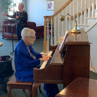 An elderly person playing the piano in a cozy indoor setting.