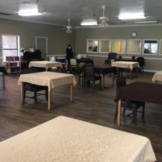 An empty dining hall with neatly arranged tables and chairs.