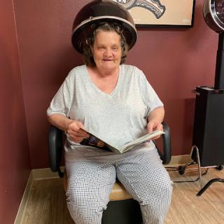 A woman enjoying a relaxing moment at the hair salon while reading a magazine under the dryer.