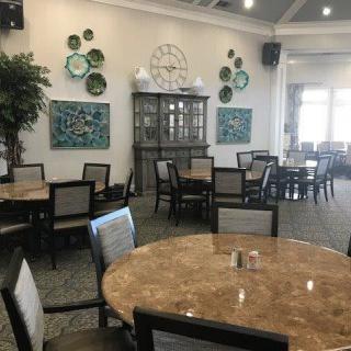 A spacious dining area with neatly arranged tables and chairs, decorated with wall art and plants.