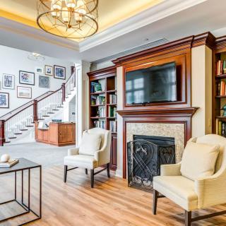A cozy living room featuring a fireplace, built-in bookshelves, and elegant seating.