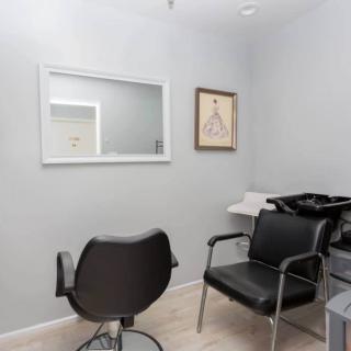 A minimalist hair salon interior featuring chairs, a mirror, and a washing sink.