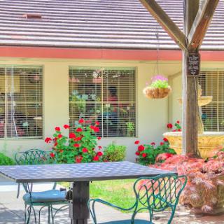 A serene outdoor dining area surrounded by vibrant flowers, perfect for enjoying the fresh air.