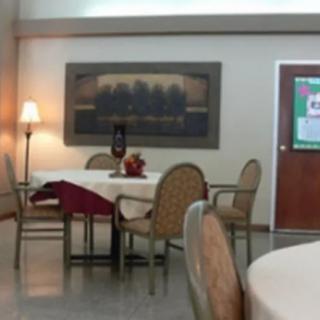 A cozy dining area featuring a table with chairs, decorated with artwork and a lamp.