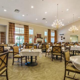 An elegant dining room featuring chandeliers, neatly arranged tables, and chairs.