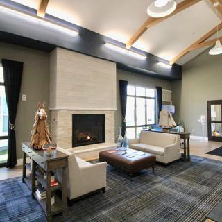 A modern living room with a cozy fireplace and ample seating, featuring large windows and stylish decor.