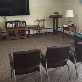 A cozy living room setup with chairs facing a television, accompanied by a lamp and bookshelf.