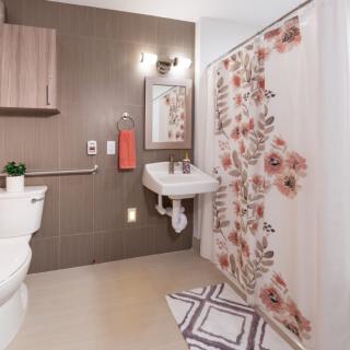A modern bathroom with a floral shower curtain and a wall-mounted sink.