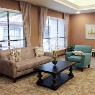 A cozy living room with a sofa, armchair, coffee table, and large windows.