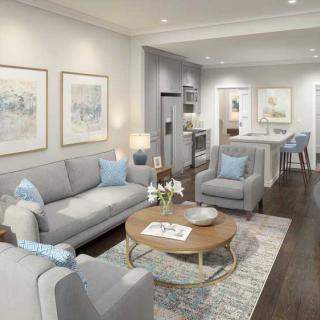 A modern living room with an open floor plan connecting to the kitchen, featuring soft color tones and contemporary furniture.