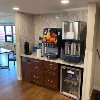 A modern beverage station featuring a coffee maker, water dispenser, and refrigerator in a well-designed kitchen area.