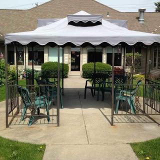 A patio area with a canopy and garden chairs.