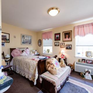 A cozy and vintage-style bedroom with decorative elements, featuring a bed with lace coverings and framed photographs adorning the walls.