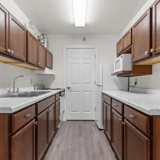 A modern kitchen with wooden cabinets and a sleek floor design.