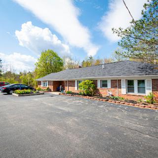 A well-maintained residential building with a landscaped front and ample parking space.