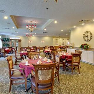A spacious dining area with neatly arranged tables and chairs, featuring elegant lighting and decor.