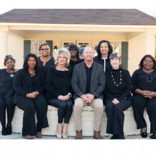 A group of people sitting together outdoors, posing for a team photo.