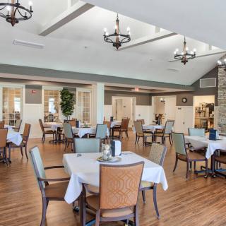 Spacious dining area with neatly arranged tables and elegant chandeliers.