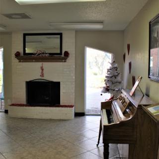 A cozy living room featuring a piano, a fireplace adorned with decorations, and an inviting entrance.