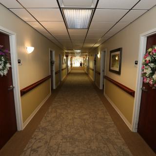 A long, carpeted hallway with multiple doors and floral decorations.