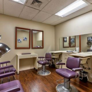 A cozy hair salon interior with purple chairs, mirrors, and a wooden floor.